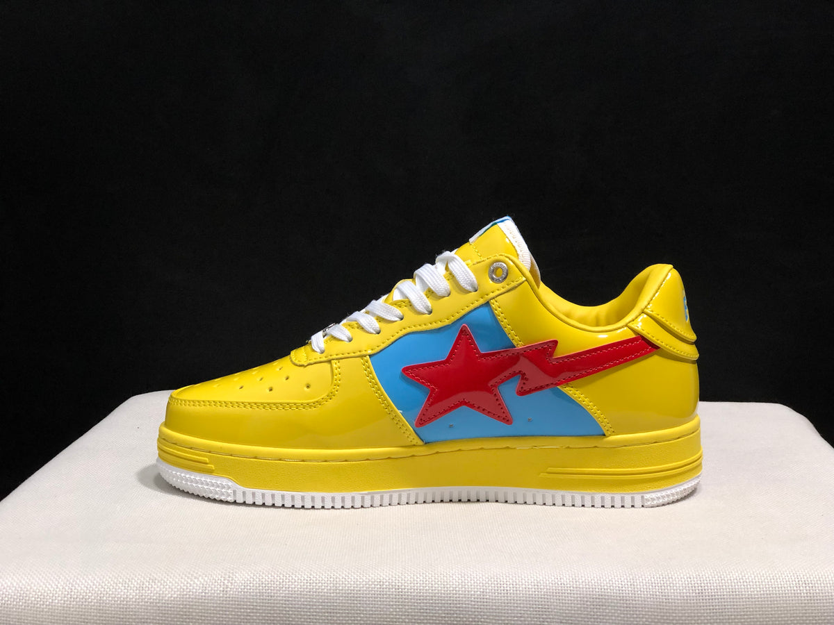 Side profile of one yellow sneaker showing the large red star graphic over a blue panel and BAPE lettering on the midsole.