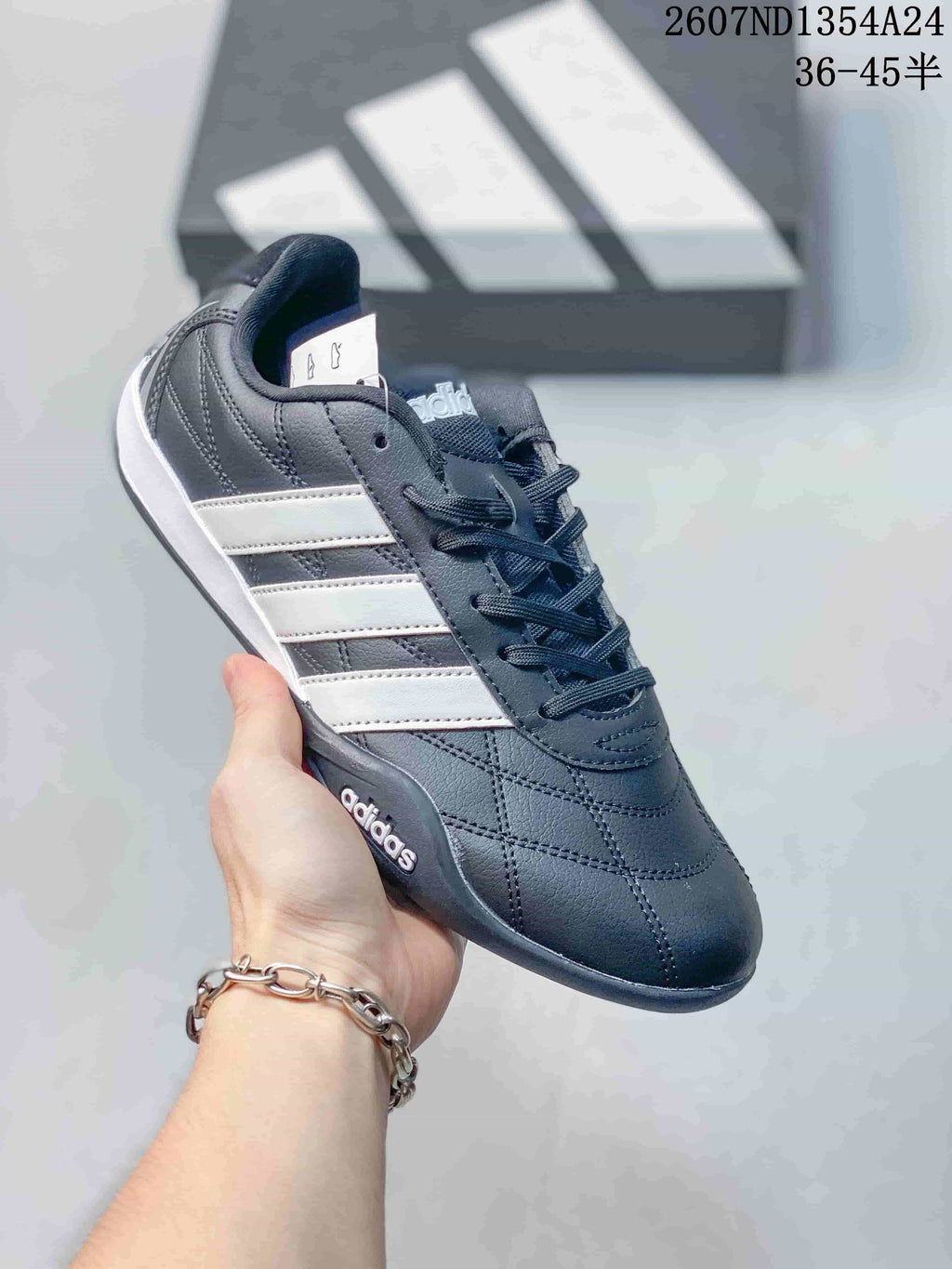Angled side view of the adidas trainer showing the dark upper, white stripes and low-profile sole.