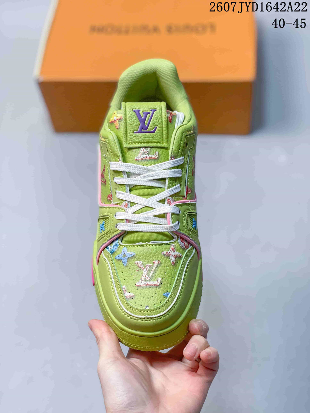 Top view of the green sneaker showing the white laces, padded tongue, decorative motifs, and branded toe panel.