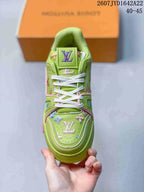 Top view of the green sneaker showing the white laces, padded tongue, decorative motifs, and branded toe panel.