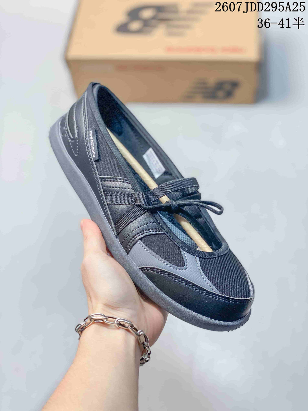 Angled side view showing the black and gray upper, New Balance side branding, strap, laces, and low-profile outsole.