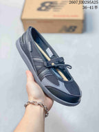 Angled side view showing the black and gray upper, New Balance side branding, strap, laces, and low-profile outsole.