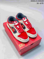 Pair of red, cream, and dark gray Nike SB Dunk Low sneakers on a red horse-themed box