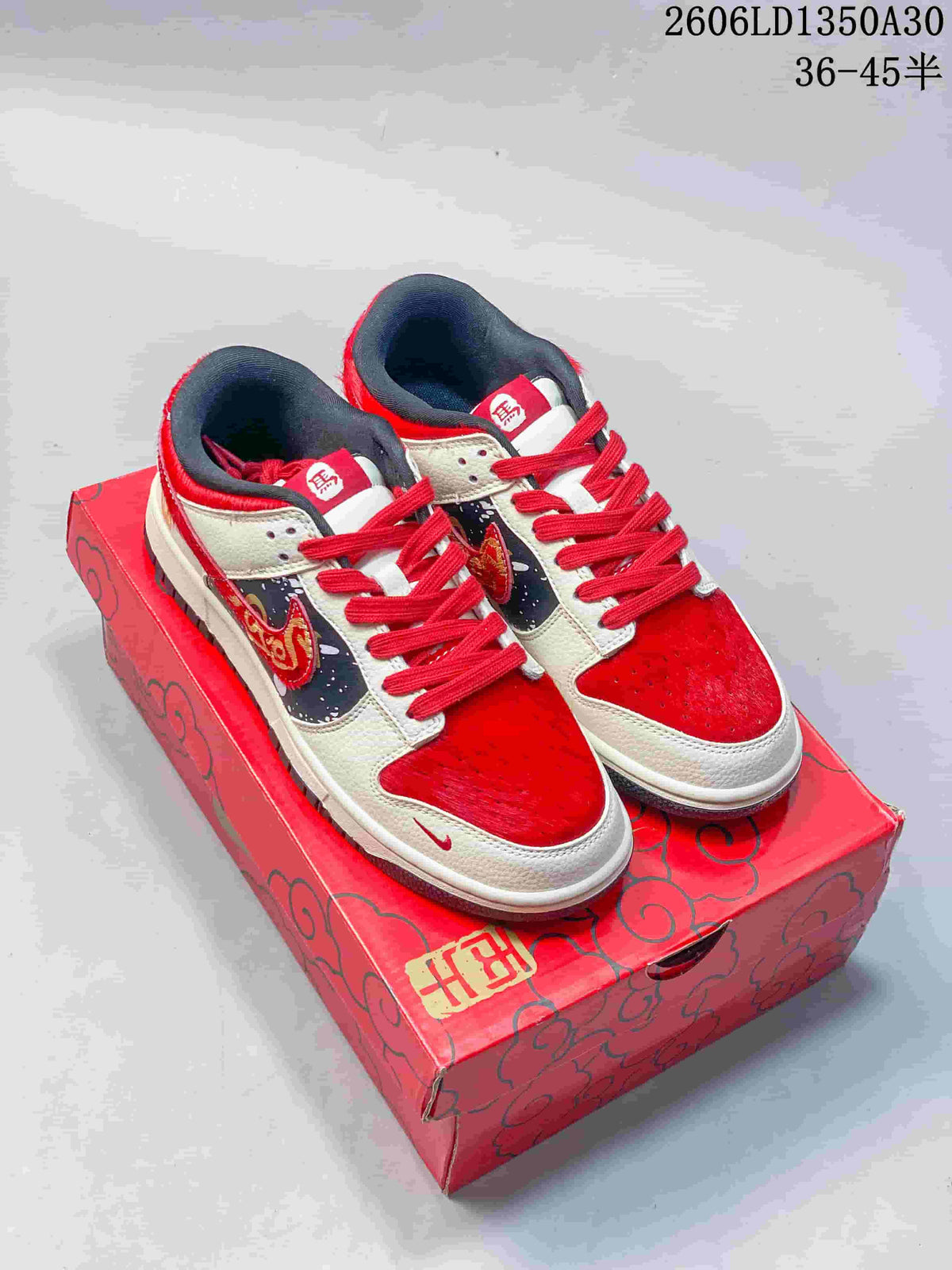 Pair of red, cream, and dark gray Nike SB Dunk Low sneakers on a red horse-themed box