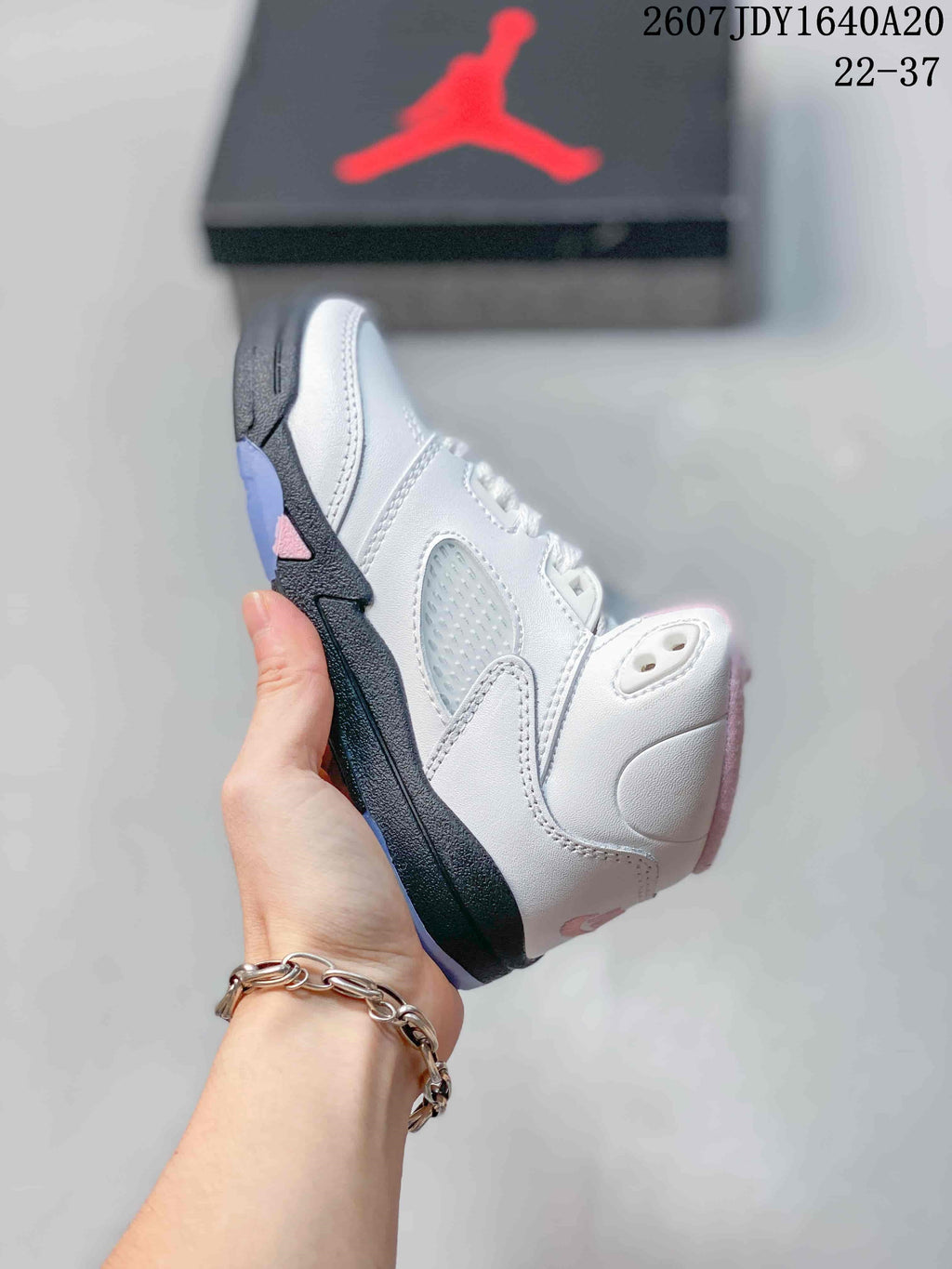 Side view highlighting the white upper, translucent mesh-style panel, black midsole, and pink accent.