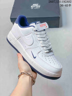 White low-top sneaker with blue collar lining, blue outsole accents, perforated toe and side Swoosh.