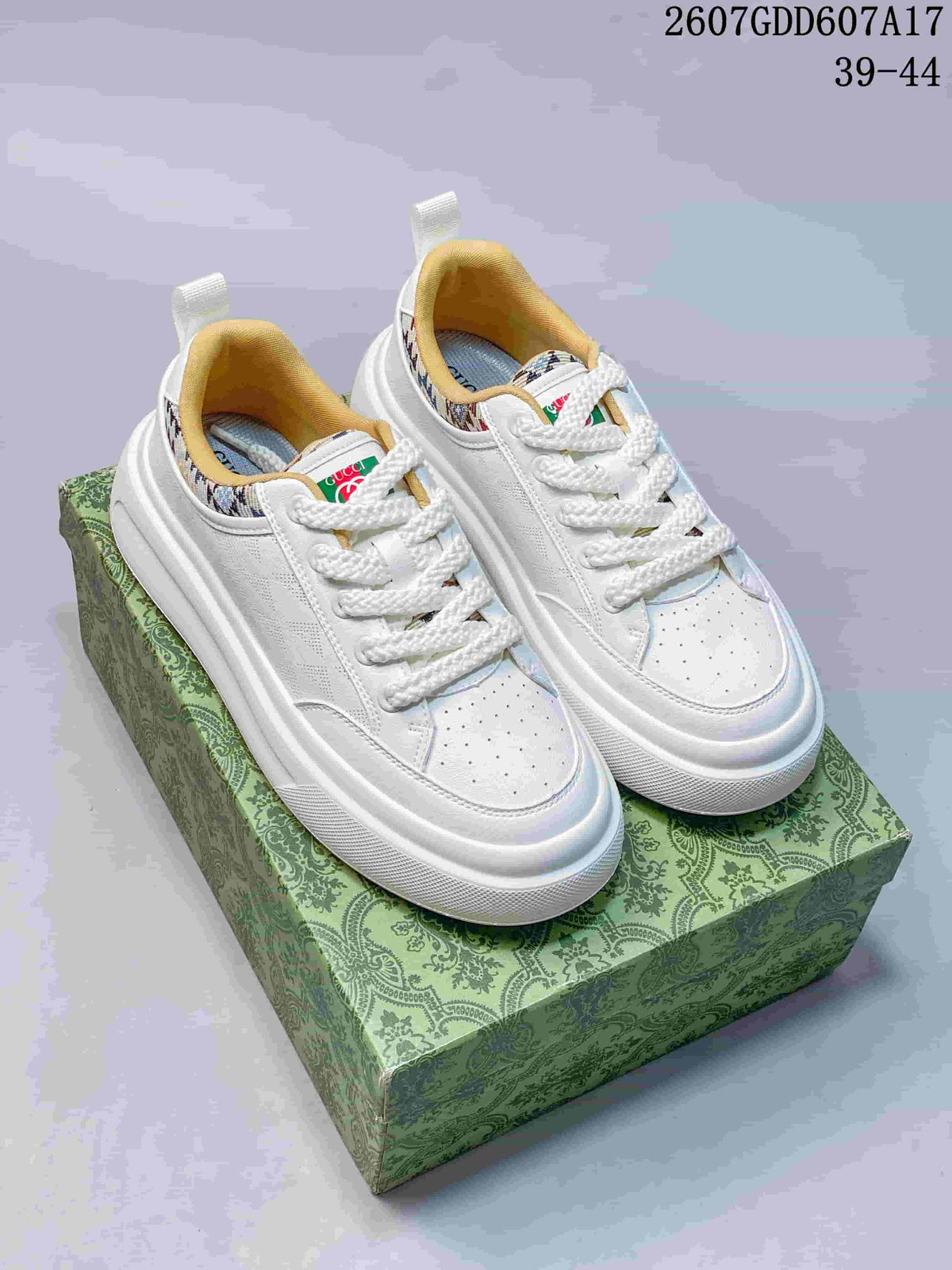 Pair of white Gucci Screener GG sneakers displayed on a patterned green box.