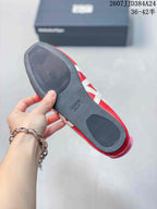 Close view of the black outsole showing textured tread zones and an embossed Onitsuka Tiger mark; the red-and-white upper is visible at the edge.
