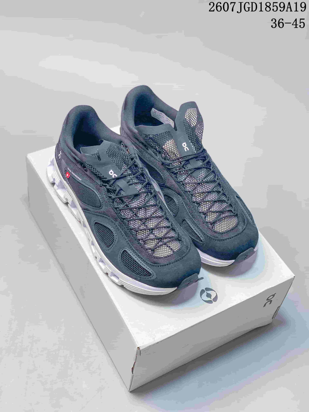 Pair of black On sneakers displayed on a branded shoebox, with white segmented soles and style code 2607JGD1859A19 visible above.
