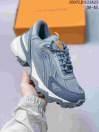 Close-up side view of a gray-blue Louis Vuitton Summit sneaker with contrasting gold tongue detail, layered panels, and a rugged outsole.