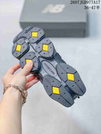 Underside view of a New Balance 9060 sneaker showing the segmented black outsole with yellow traction sections and New Balance branding.