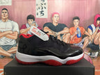 Side view of a black and red Air Jordan 11 sneaker with a visible AJ-11 tag.