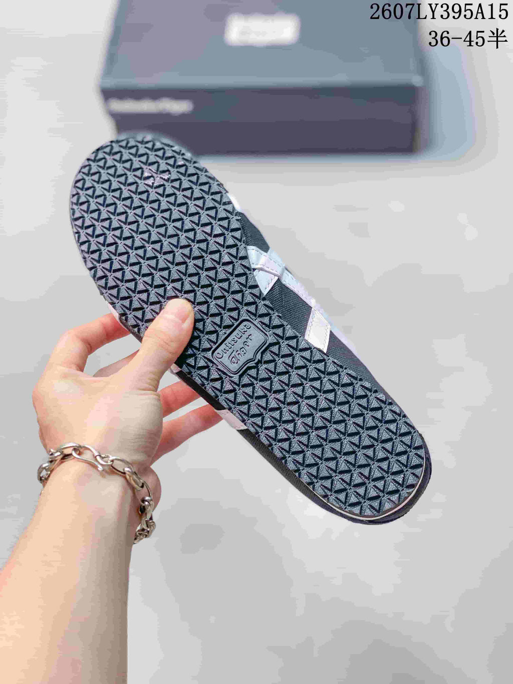 View of the black sneaker outsole showing a repeating geometric tread pattern and an Onitsuka Tiger outsole badge.