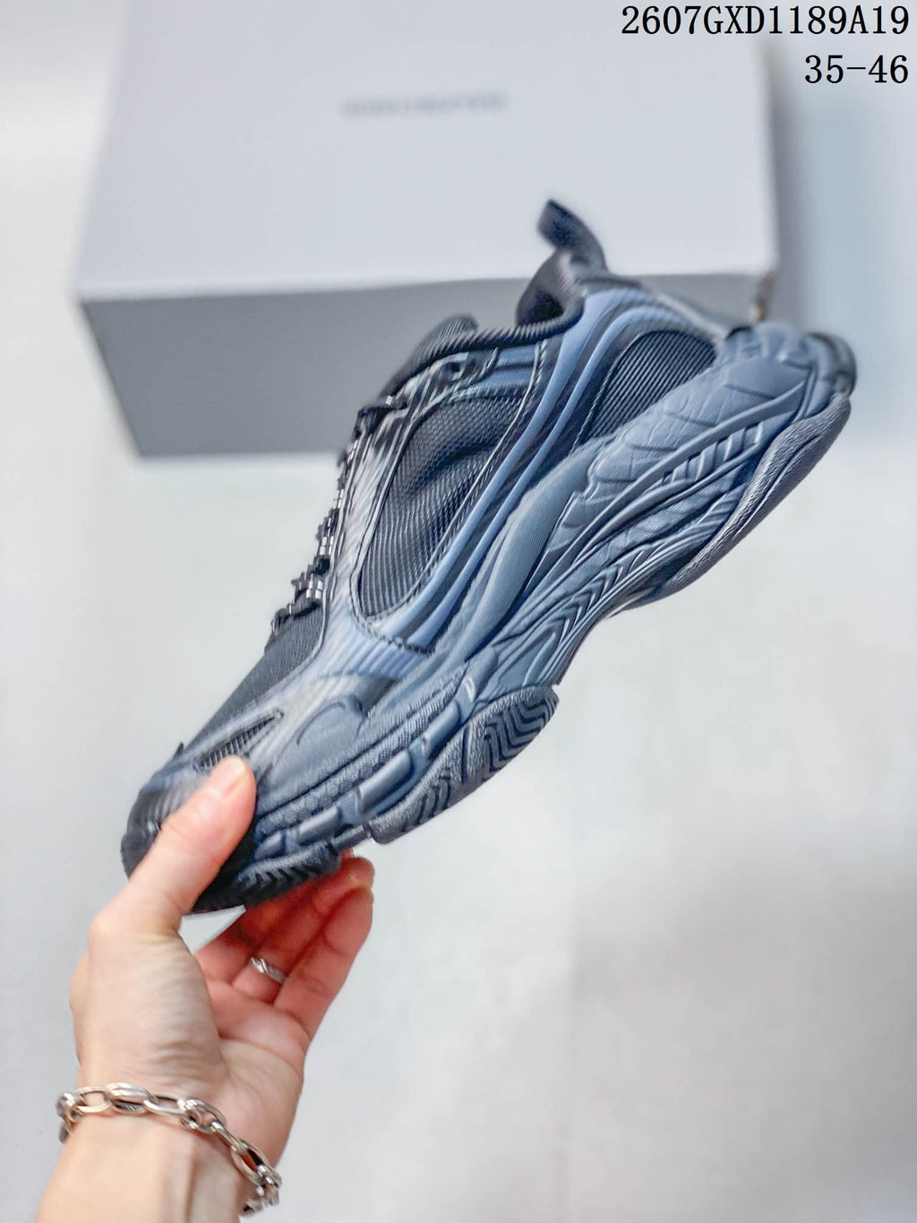 Side profile of a black and dark gray Balenciaga Triple S.2 sneaker showing its layered chunky sole.