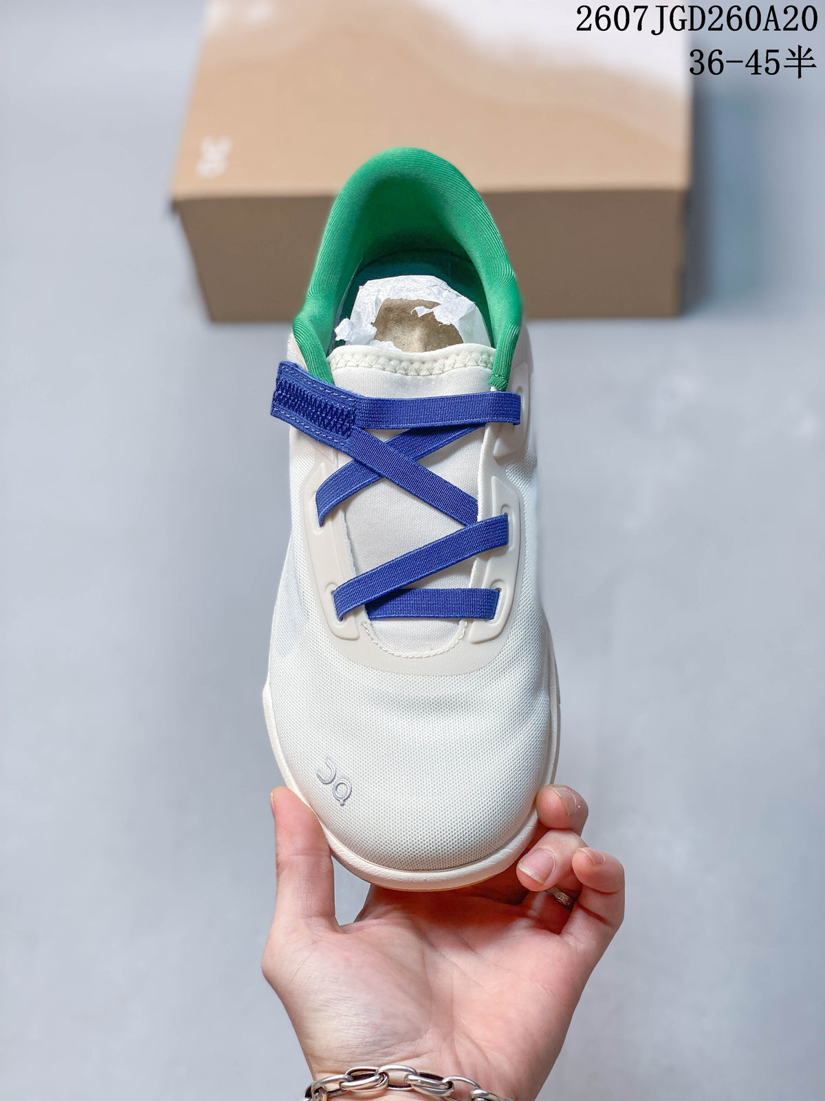 Top view of the sneaker showing the white upper, blue crossing straps, green collar lining, and rounded toe.