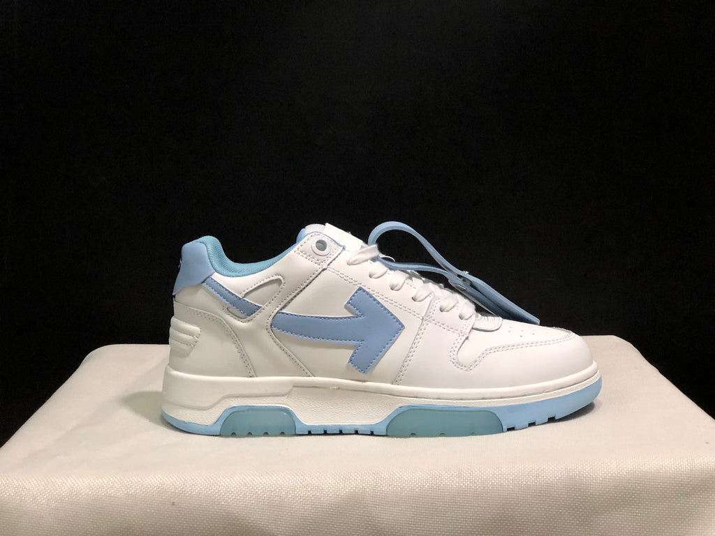 Close side profile of a white sneaker with light blue arrow-style side detailing, padded collar and layered sole.