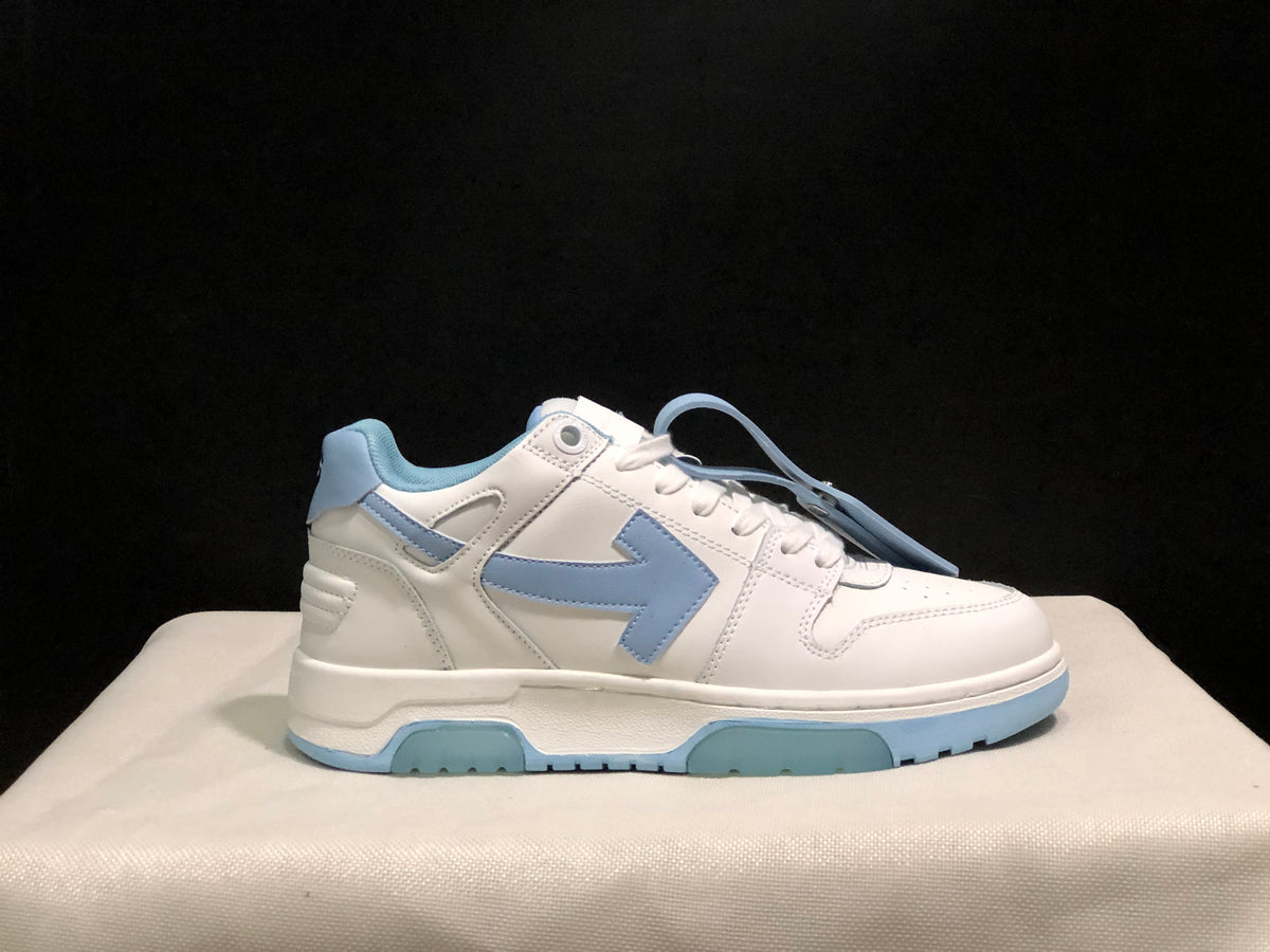 Close side profile of a white sneaker with light blue arrow-style side detailing, padded collar and layered sole.