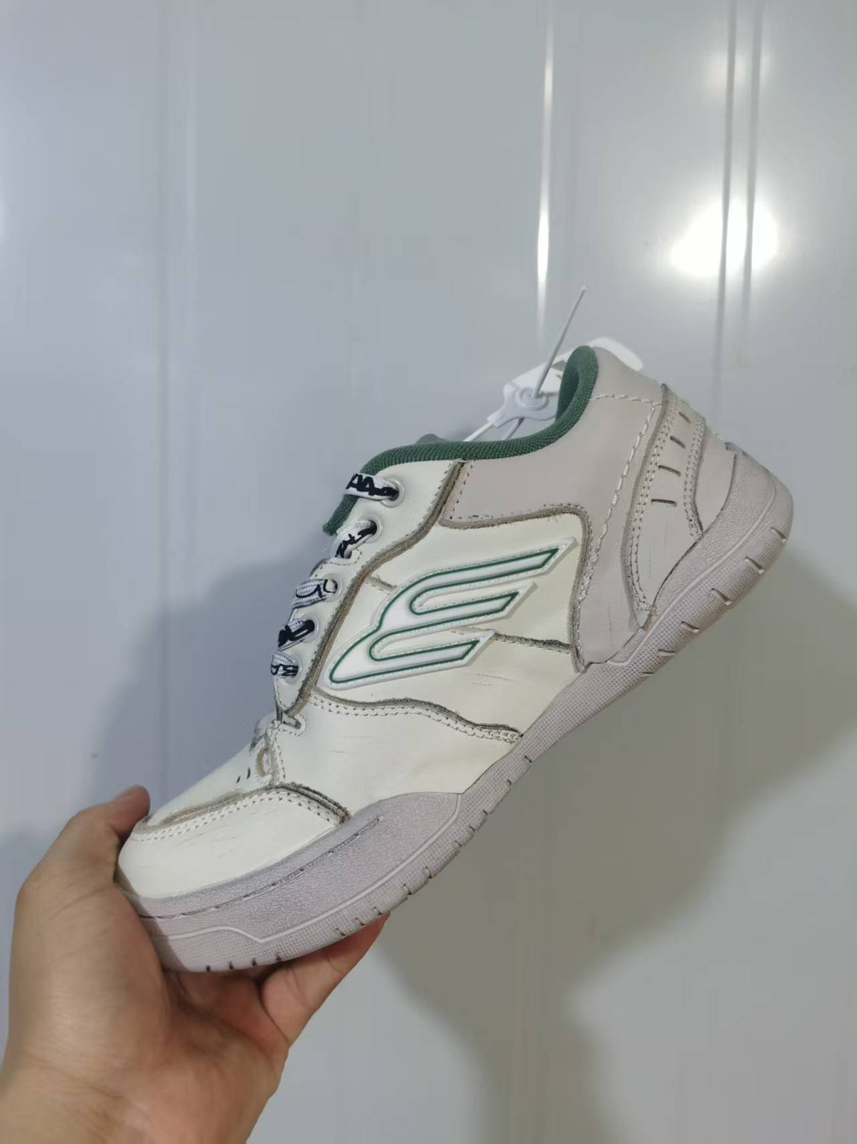 Close angled view of the beige and green Balenciaga Hamptons sneaker showing the side branding, stitched panels, and rubber sole.