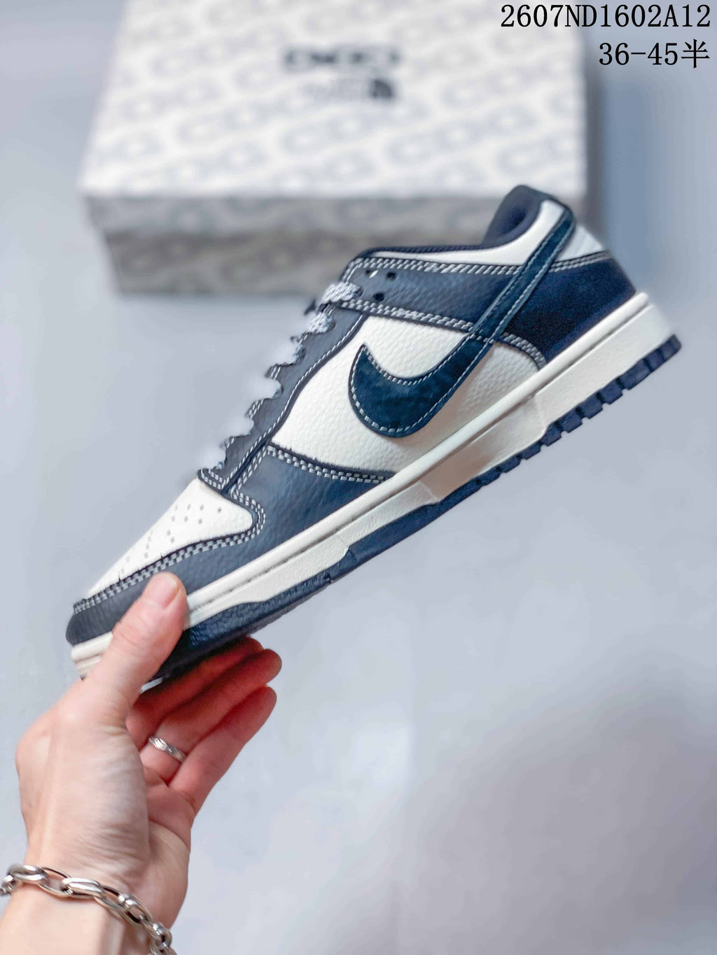 Side profile of the sneaker showing the dark navy Swoosh, off-white panels, layered construction and dark outsole; product code and a 36–45 size range are overlaid above.