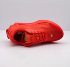Top-side view of one red sneaker highlighting the laces, tongue, textured upper, and insole branding.