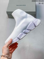 Side profile of a white sock sneaker showing the knit upper and segmented white outsole.