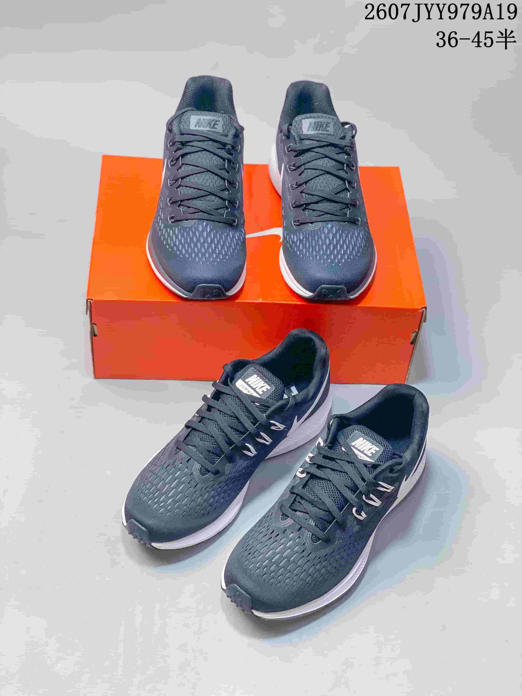 Multiple views of dark gray Nike running shoes with white details, displayed with an orange shoebox.