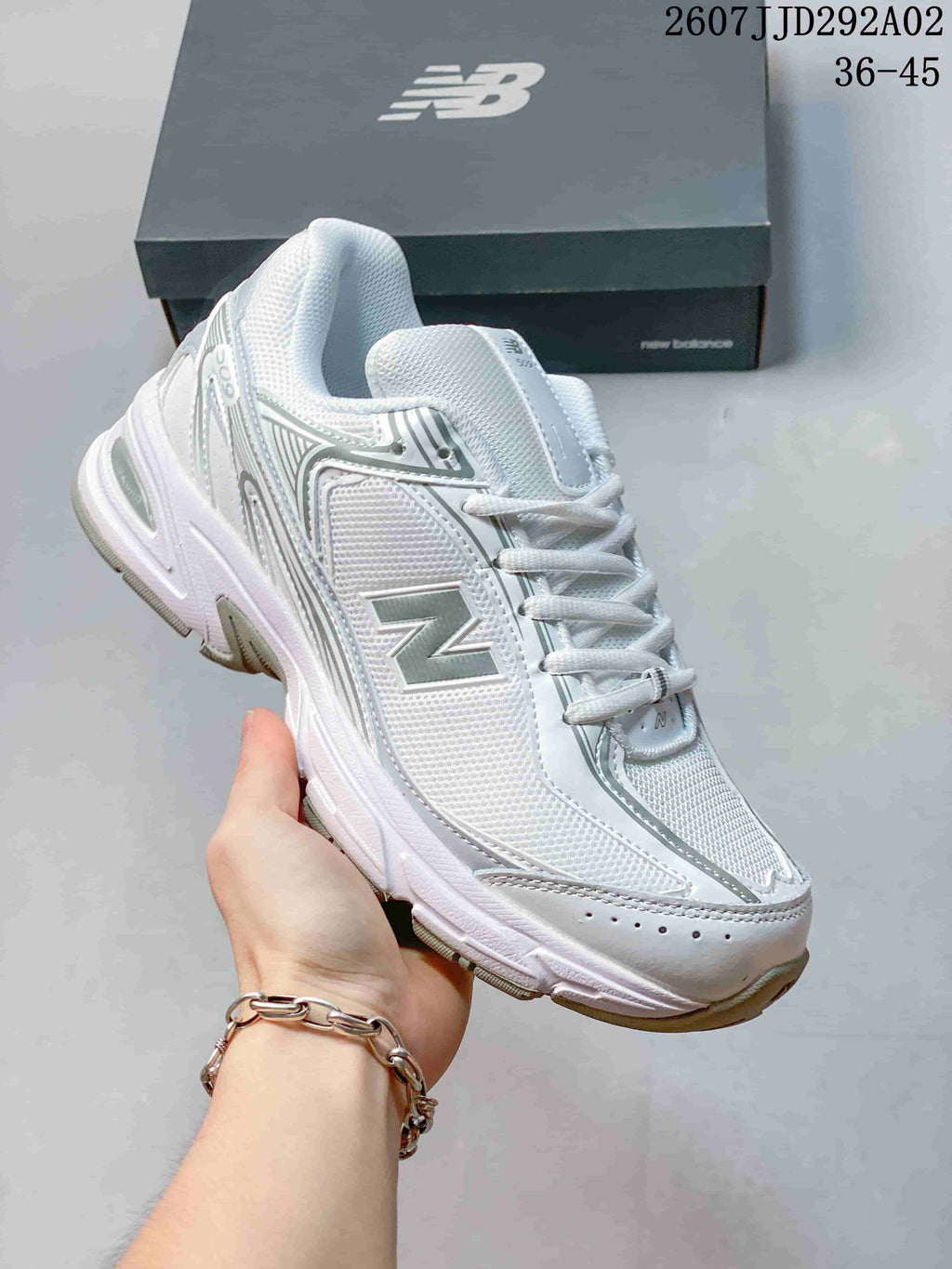 Angled side view of the white and grey New Balance 509 sneaker showing the side branding, layered upper and textured outsole.