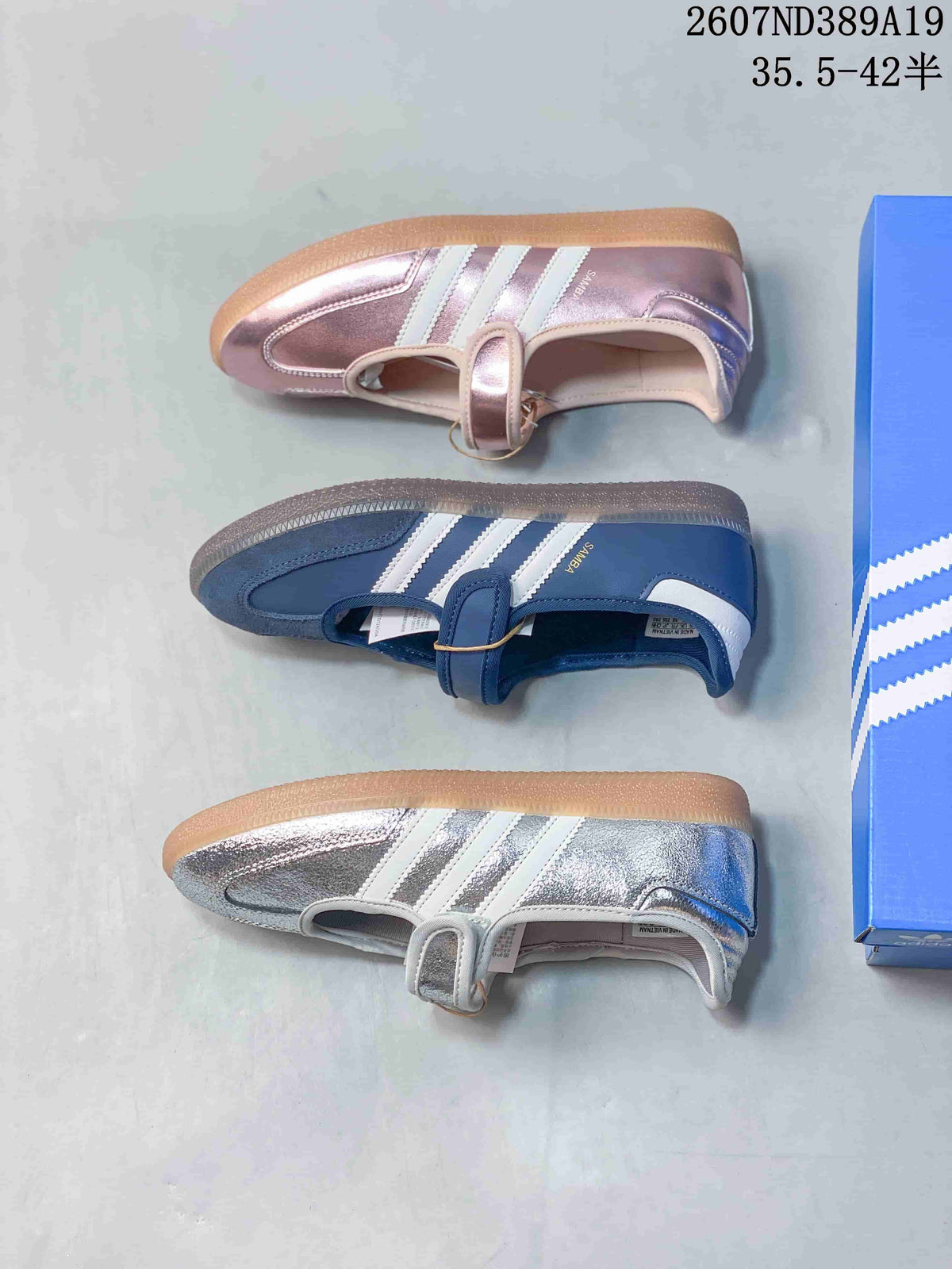 Top-down view of pink, blue, and metallic silver Samba Jane sneakers arranged beside an adidas shoebox.