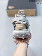 Rear view of a light gray sandal showing the padded heel area, lace toggle, outsole tread, and visible surface-control text.