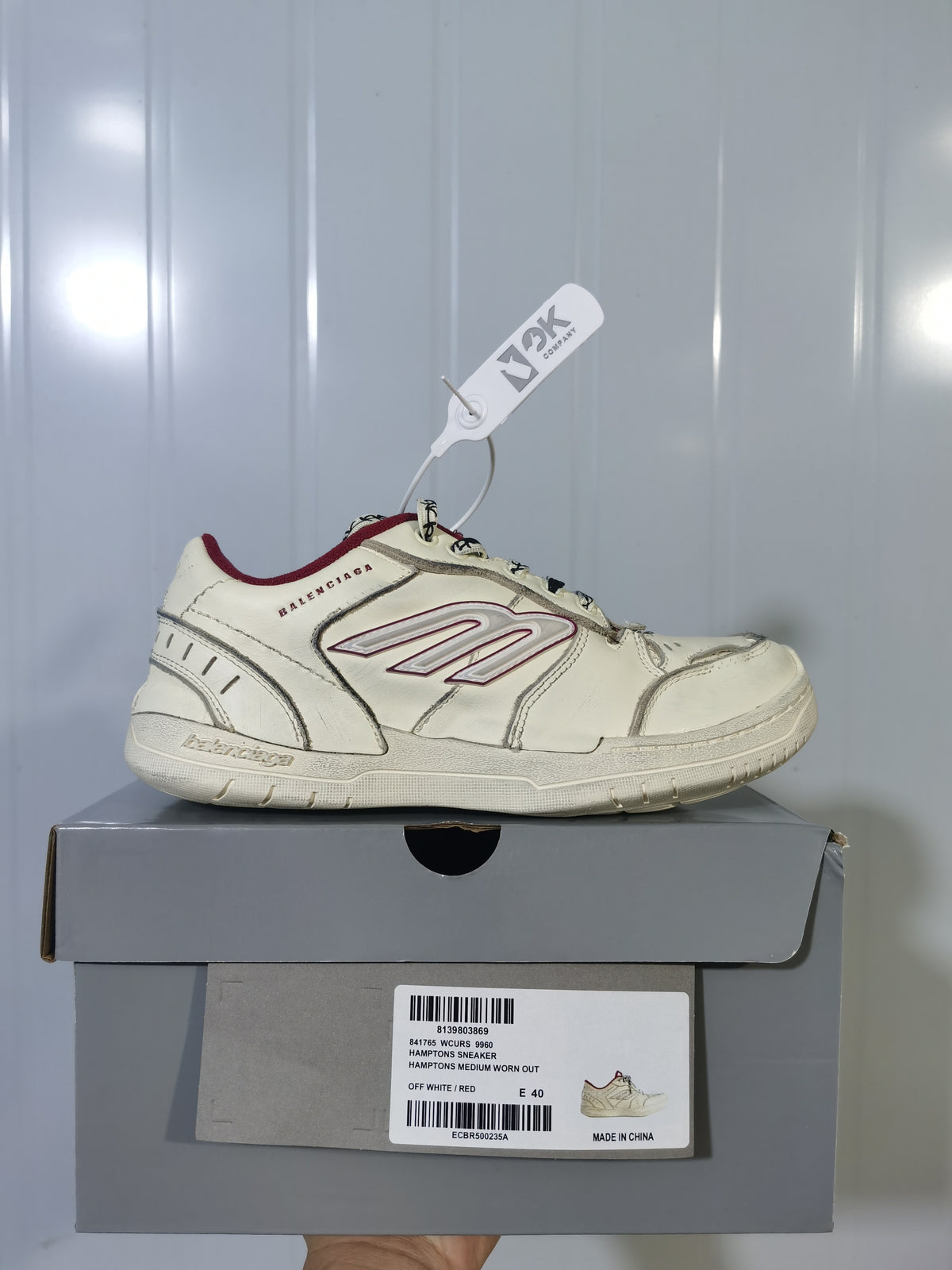Side view of an off-white Balenciaga Hamptons sneaker with red accents displayed on its box; the box label shows size E 40.
