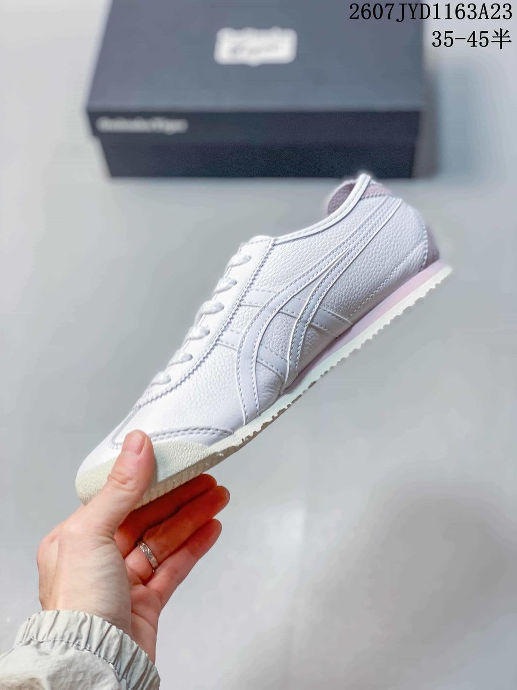 Side view showing the white low-top sneaker, layered side stripes, and pink midsole accent.