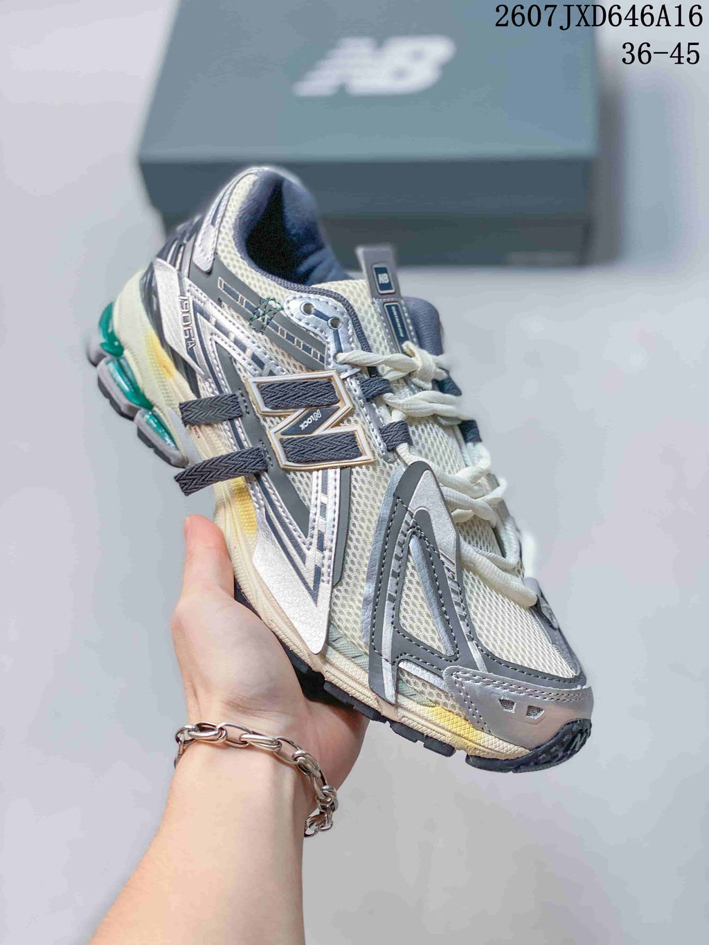 Angled side view of a New Balance 1906A sneaker showing the large side branding, mesh upper, and layered gray overlays.