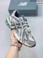 Angled side view of a New Balance 1906A sneaker showing the large side branding, mesh upper, and layered gray overlays.
