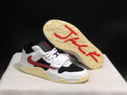 Angled view of one sneaker with the cream outsole lifted to show its textured tread and red outsole graphics.