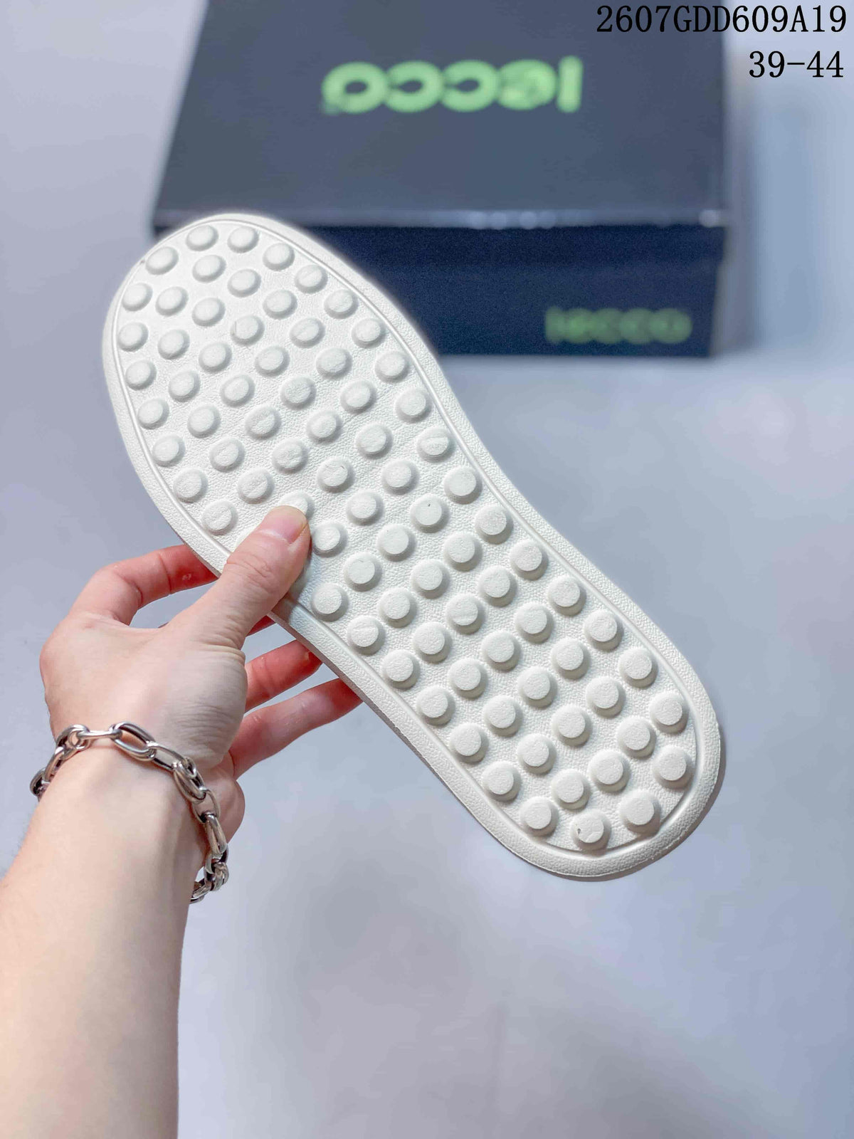 Bottom view of the sneaker showing the light-colored outsole with raised circular traction elements.