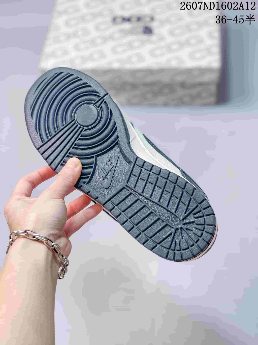 Underside view of the sneaker showing the dark rubber outsole, circular forefoot traction and rectangular tread sections; product code and a 36–45 size range are visible above.