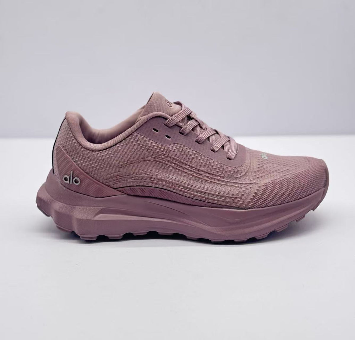 Side profile of a pink alo sneaker showing the lace-up upper, layered midsole, and side branding.
