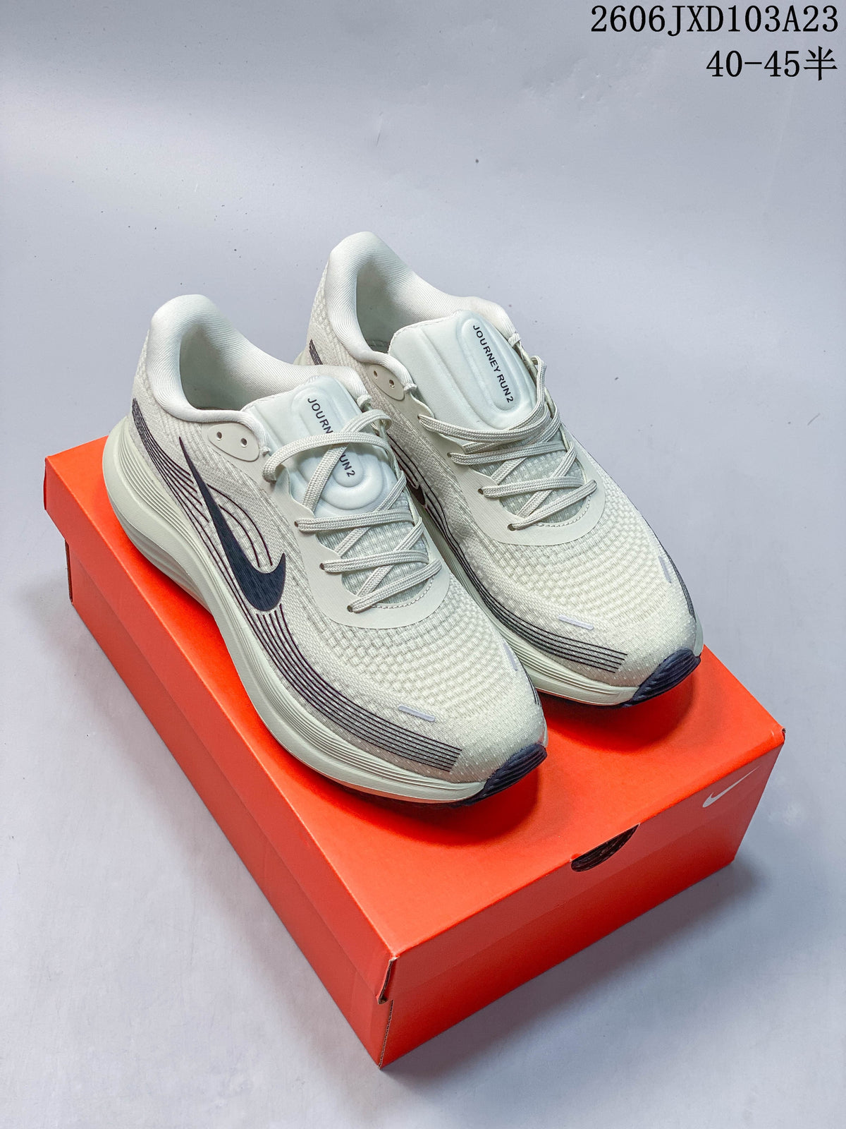 Pair of light gray Nike running shoes with dark side graphics, shown on an orange shoebox