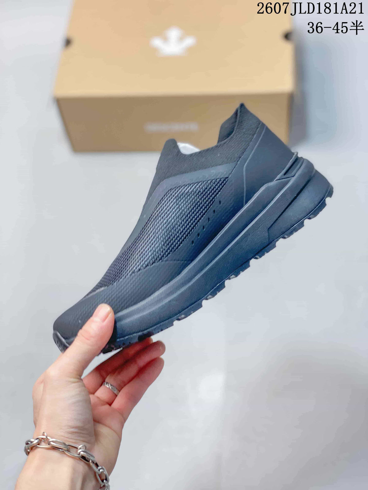 Side profile of the black slip-on sneaker showing the mesh-like upper panel, overlays and thick sole.