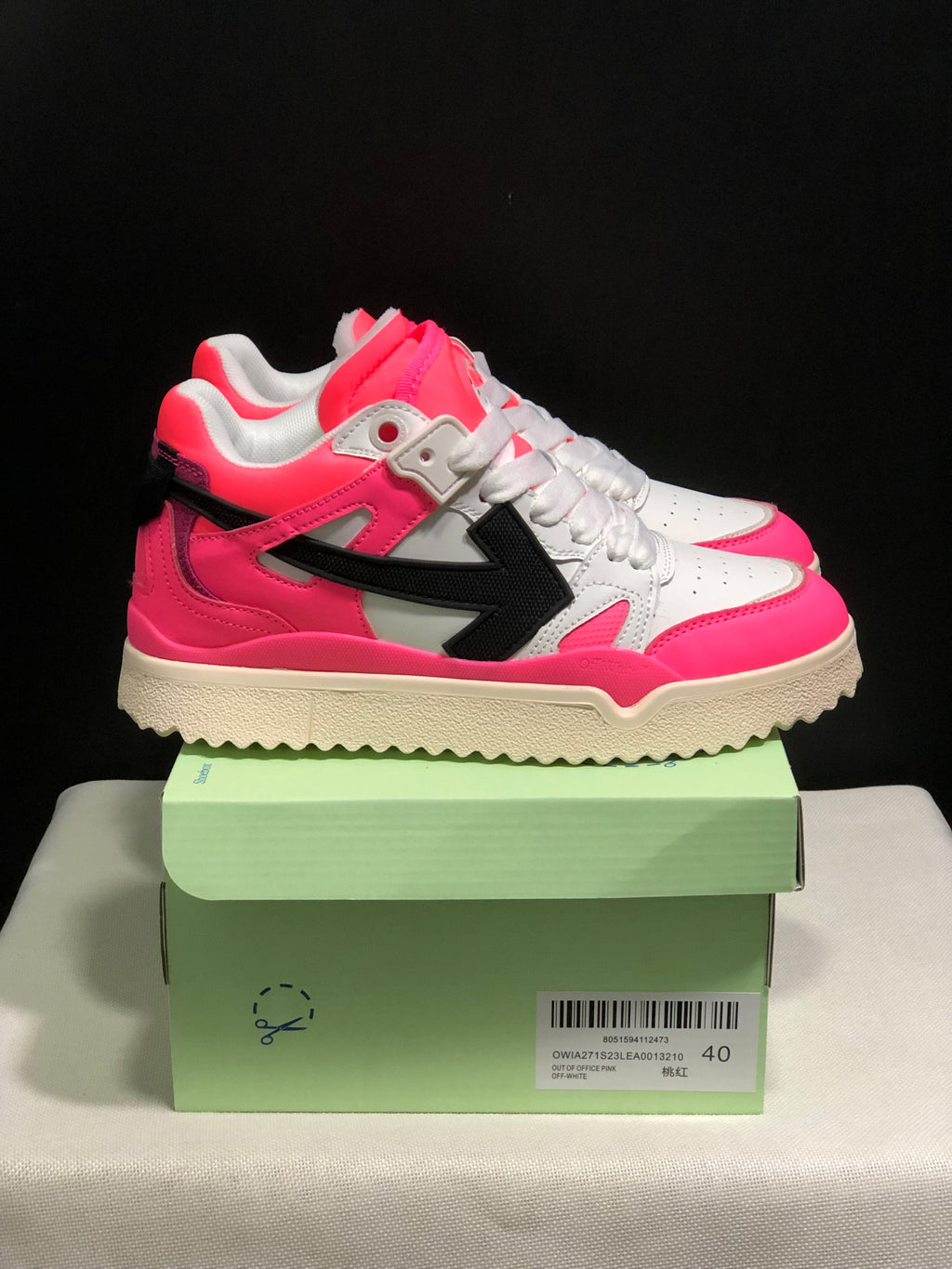 Side view of the pink and white sneakers showing the black arrow motif, white laces, and cream outsole.