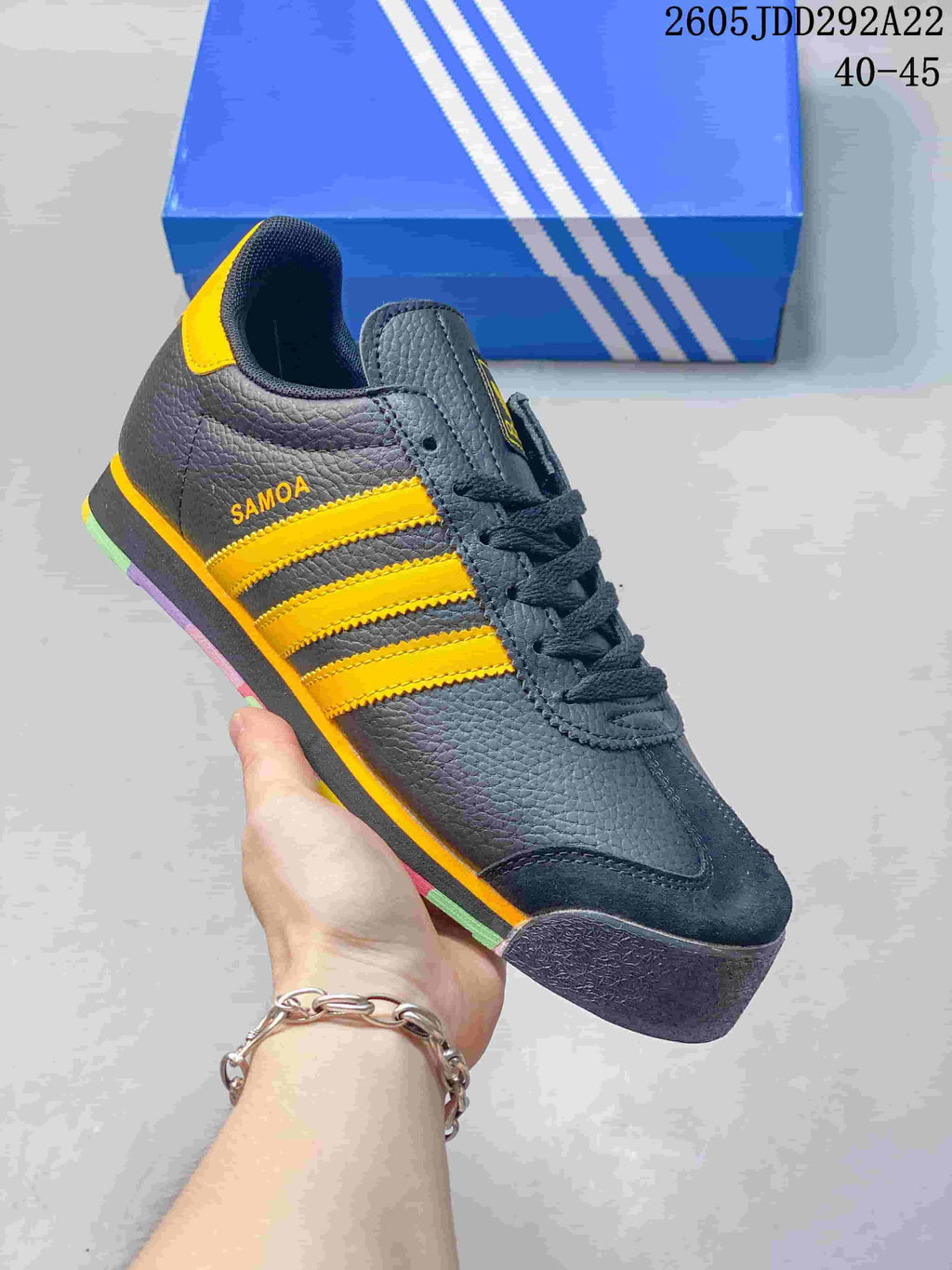 Dark Adidas Samoa sneaker with bright yellow side stripes and multicolor sole accents.