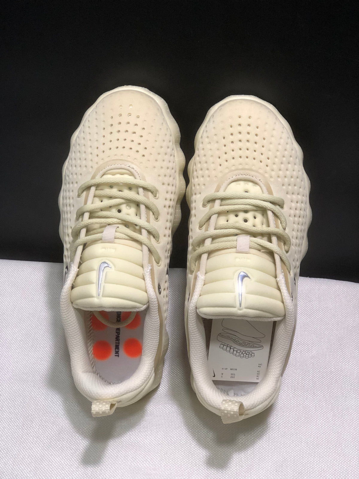 Top-down view of the pair showing cream laces, padded tongues, textured uppers, and orange accents visible inside the shoes.