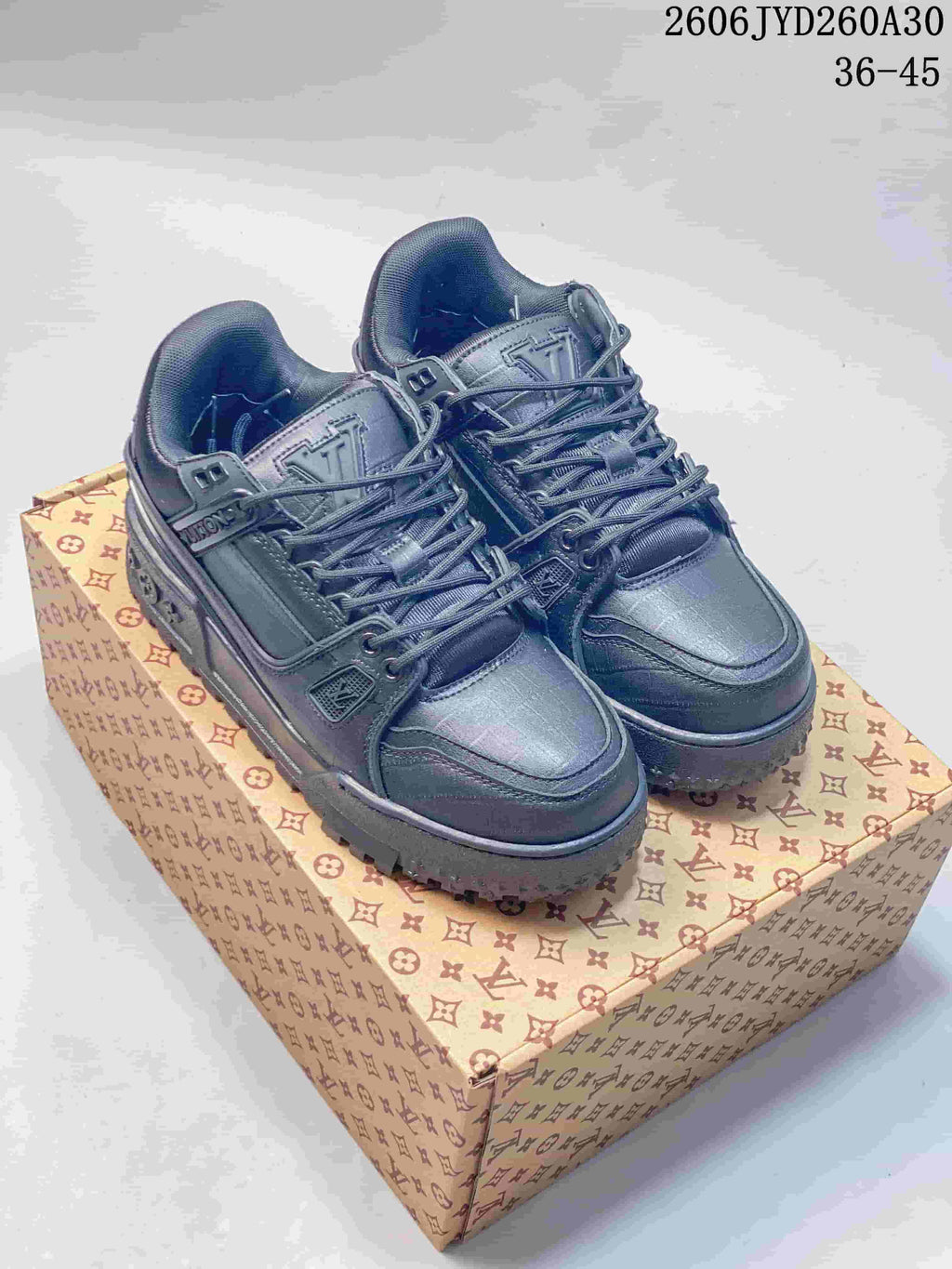 Pair of dark charcoal Louis Vuitton Trainer Maxi low-top sneakers on a patterned box