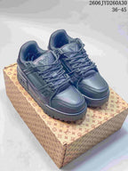 Pair of dark charcoal Louis Vuitton Trainer Maxi low-top sneakers on a patterned box