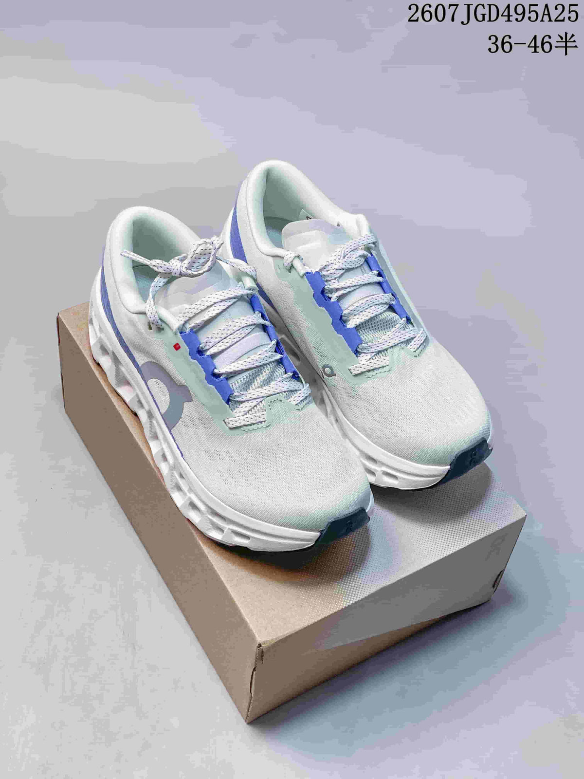 Pair of light green and blue On Cloudmonster 3 sneakers displayed on a box