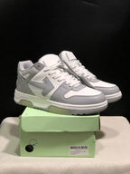 Pair of white and gray low-top sneakers displayed on a pale green shoebox from a front three-quarter view.