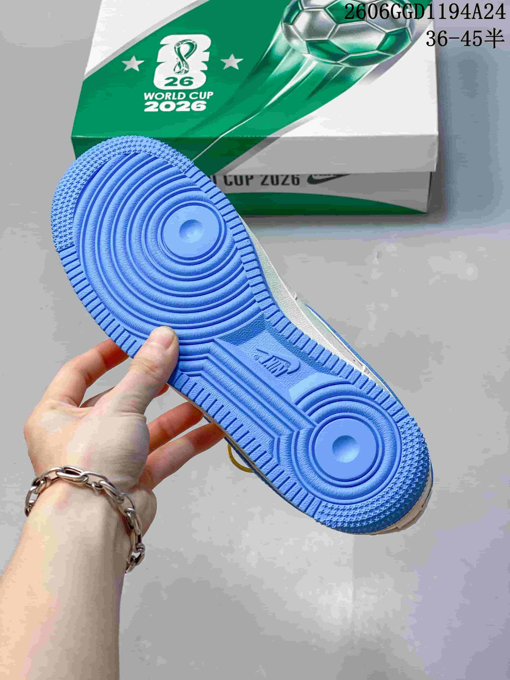 Blue outsole of the sneaker shown beside football-themed World Cup 2026 packaging.