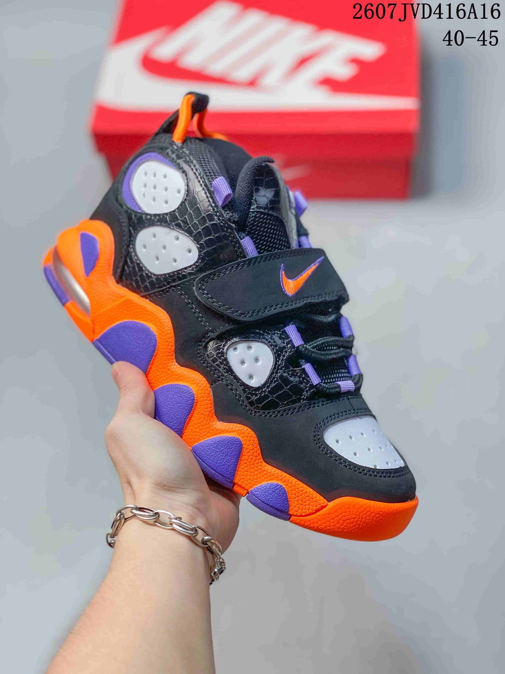 Black Nike high-top sneaker with bright orange and purple accents, perforated panels, laces and a hook-and-loop strap; style code 2607JVD416A16 and size range 40–45 are overlaid.