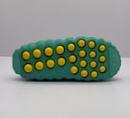 Bottom view showing the green outsole with multiple yellow circular pods and molded tread areas.