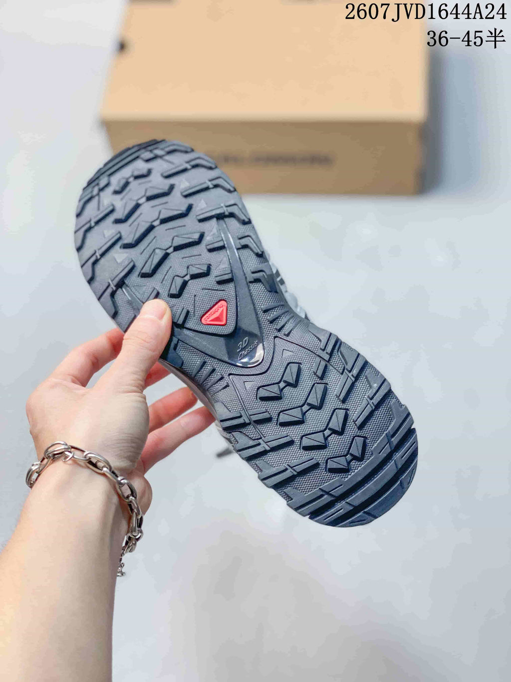 Close-up of the Salomon sneaker outsole showing a deep, multi-directional lug pattern and red outsole insert.